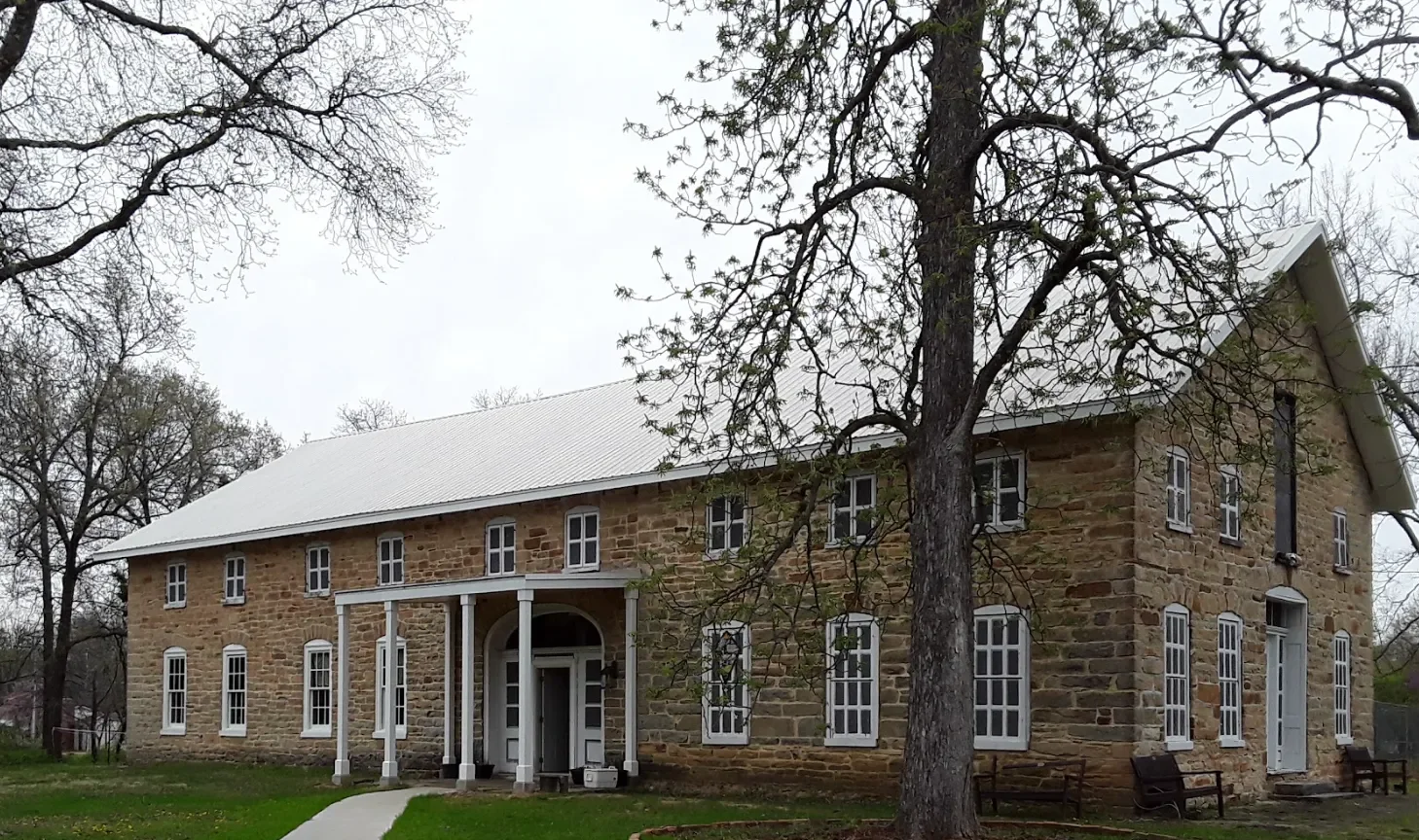 The mansion from the front lawn with a large old shade tree